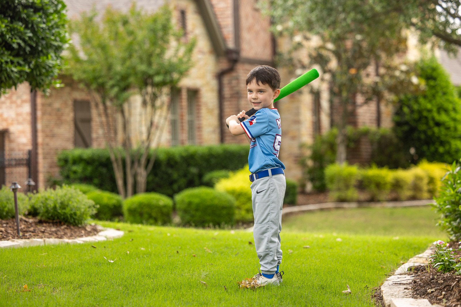 child playing baseball landscape beds green lawn 