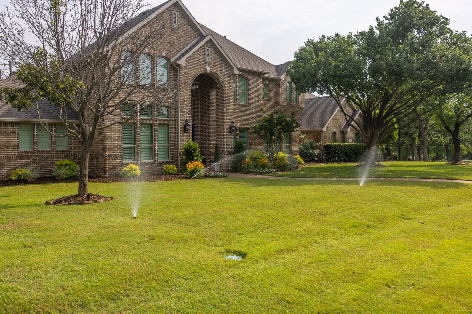 irrigation system watering large green front lawn 
