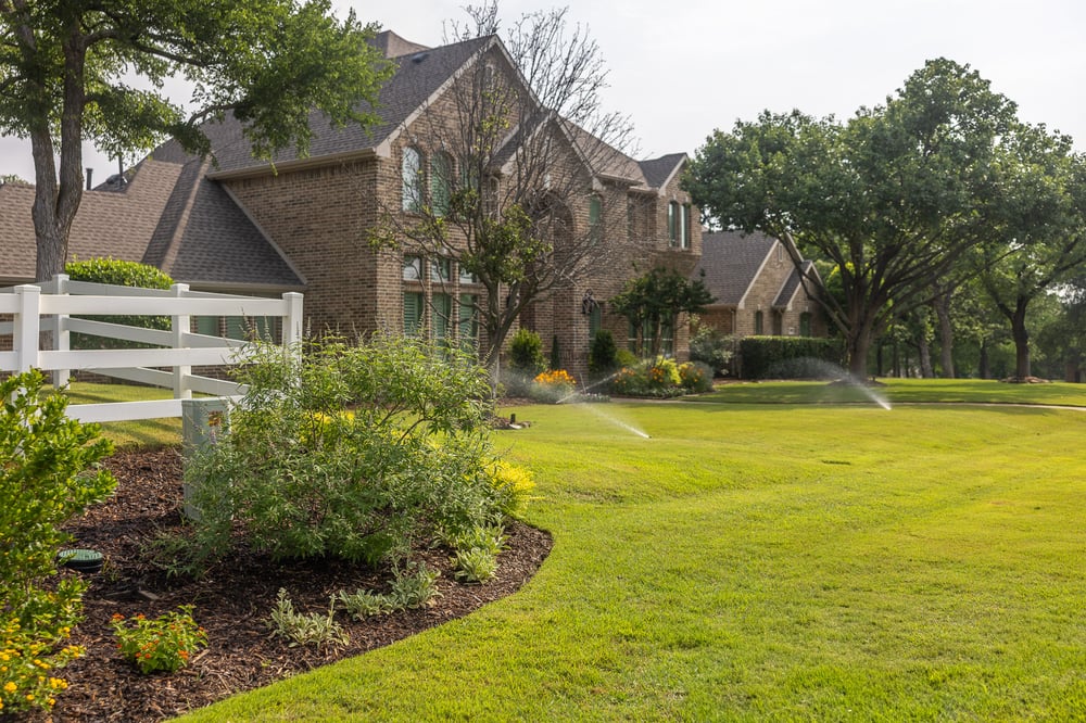 large green lawn irrigation system watering lawn front of house 
