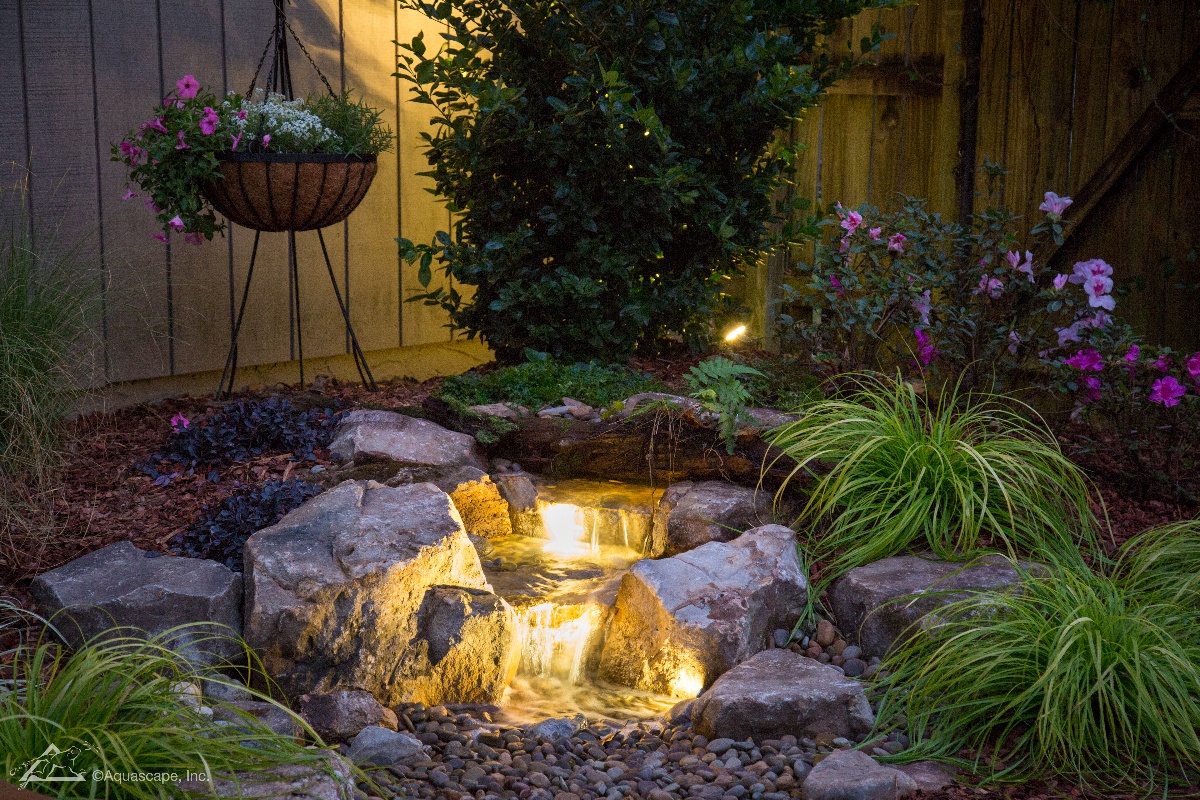 water fall with landscape lighting and plants