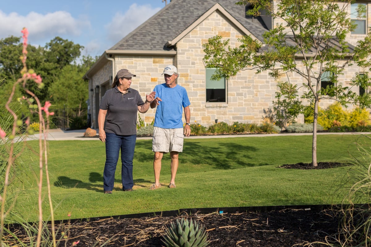 homeowner and landscape expert inspect grass