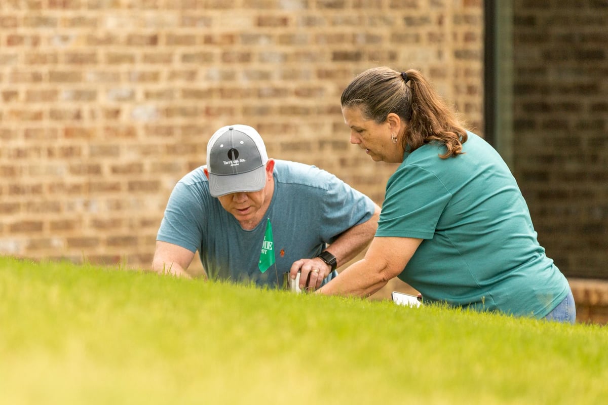 lawn care expert and homeowner inspect grass