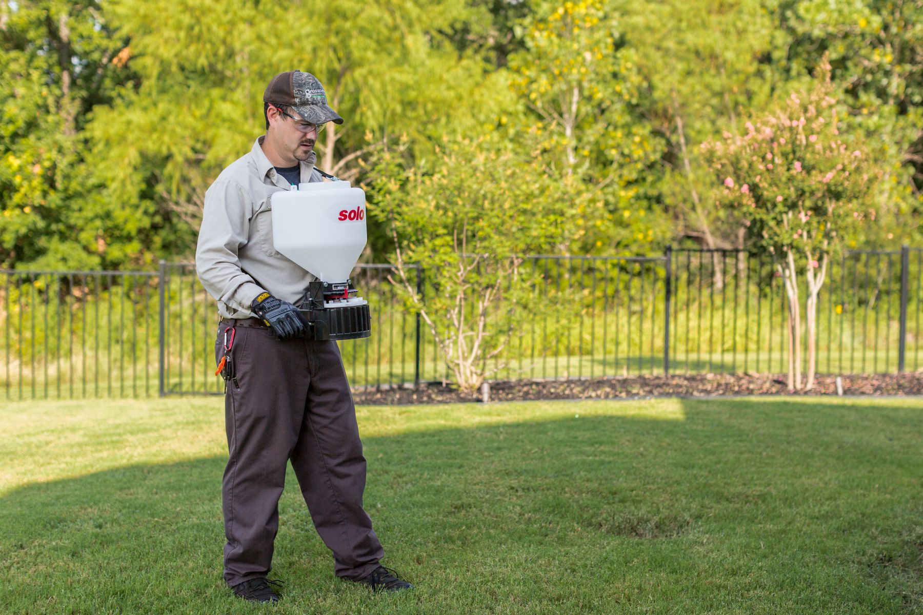 lawn care technician using hand spreader