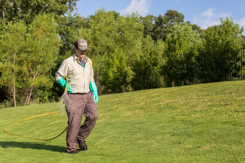 lawn care technician spraying weed control spray