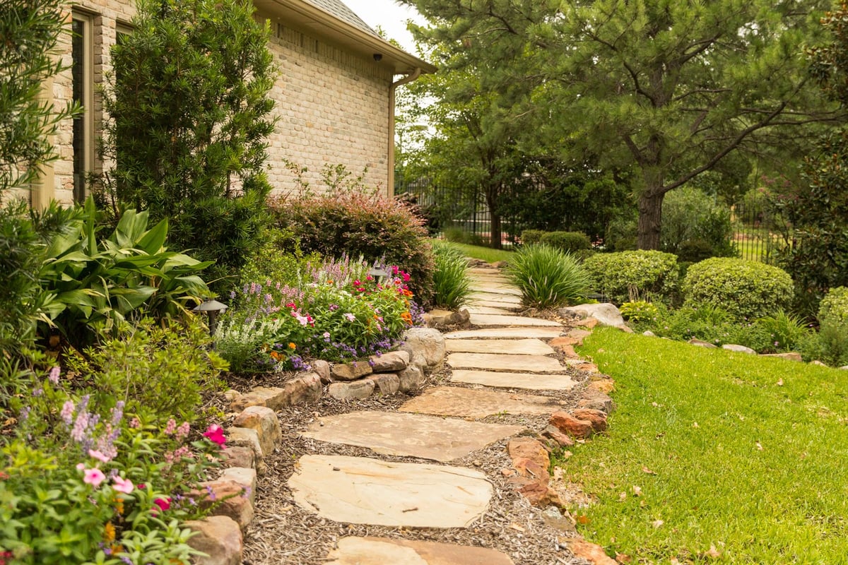 stepping stone walkway with flowers and shrubs