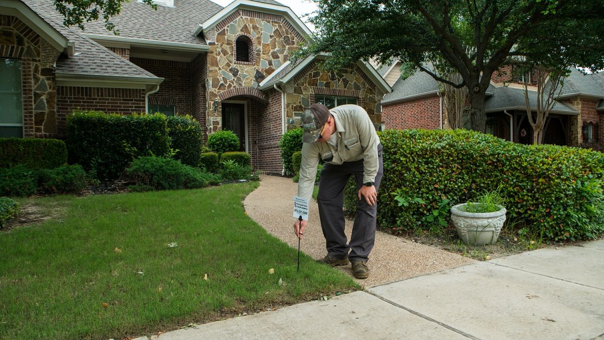 lawn care team puts fertilization notice sign in lawn