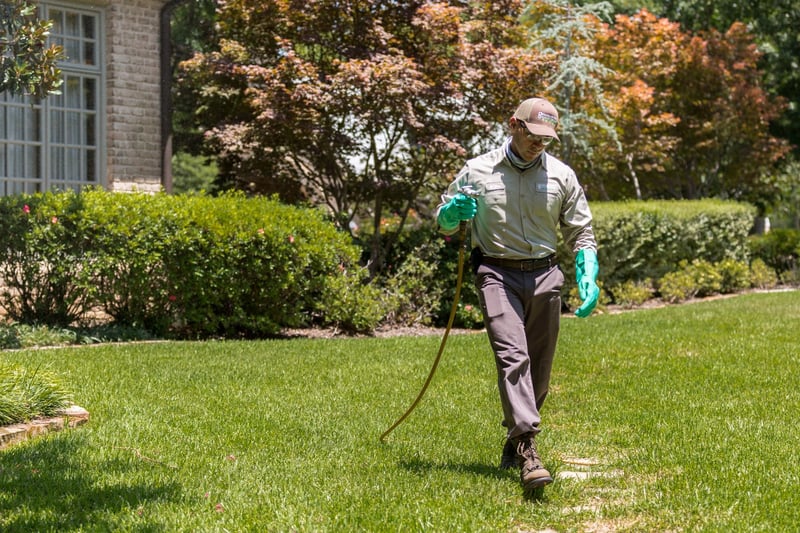 lawn care technician applying lawn treatment