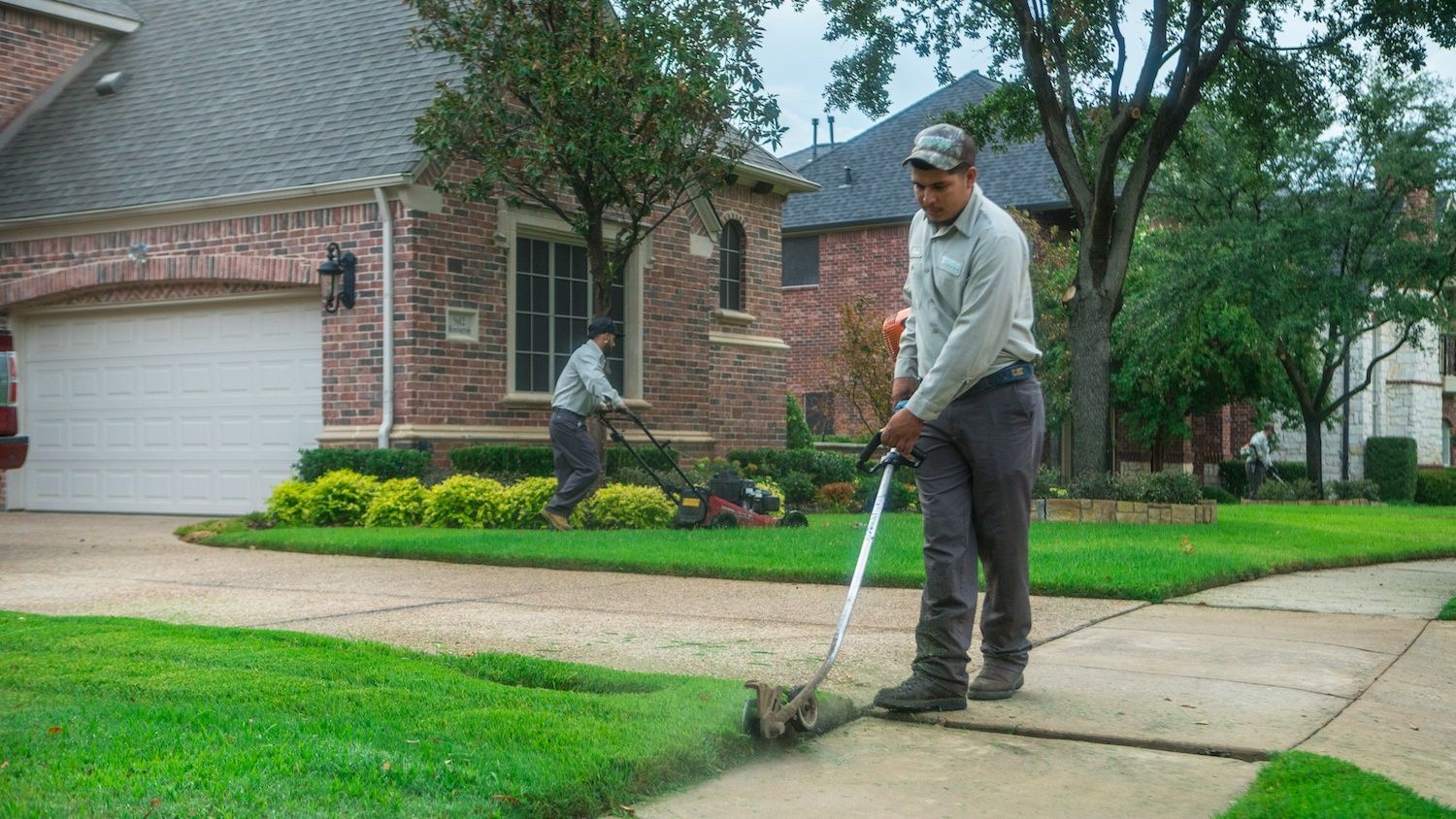 landscaping technicians mowing and trimming lawn