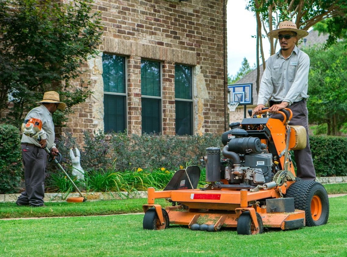 lawn care professionals mow and line trim lawn in fall