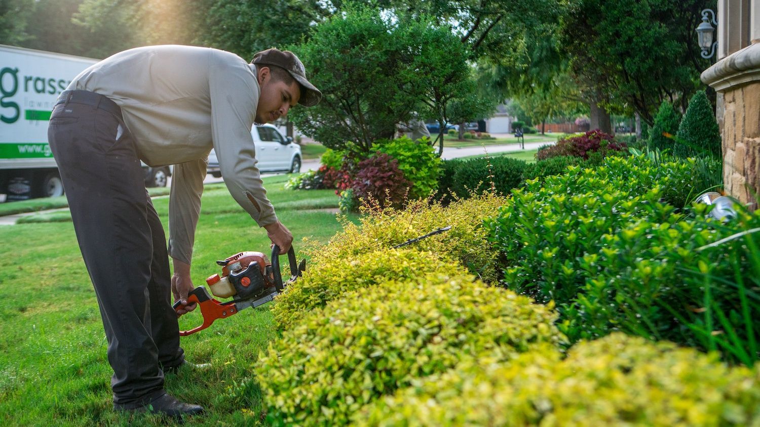 landscape technician trimming shrubs for fall maintenance