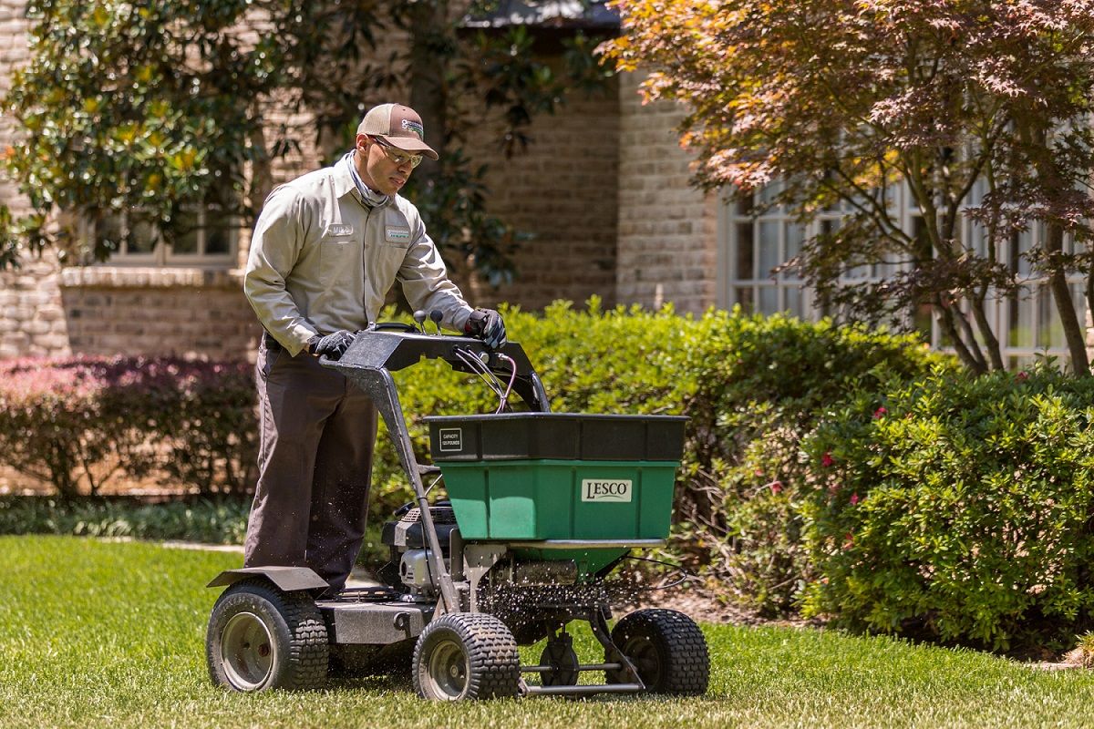 lawn care technician spreading fertilizer for job Texas