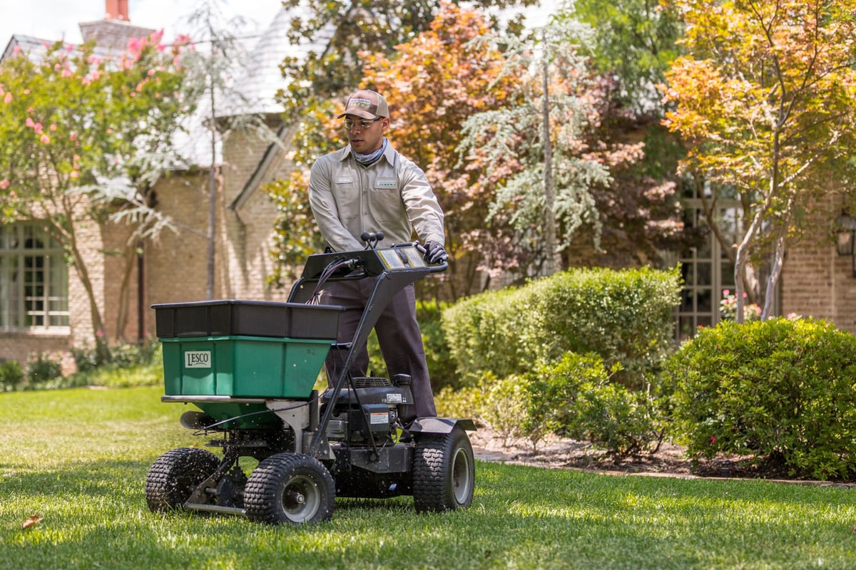 lawn care technician applying pre-emergent weed control