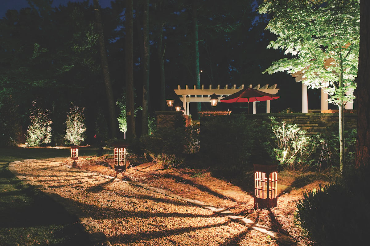 landscape lighting in backyard with pathway and pergola