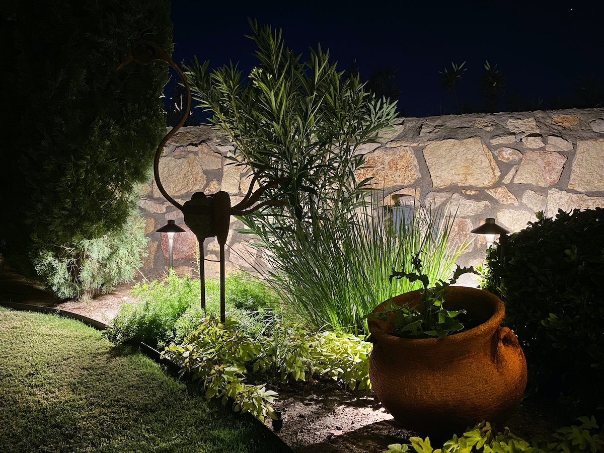 landscape lighting with retaining wall and sculpture in plantings