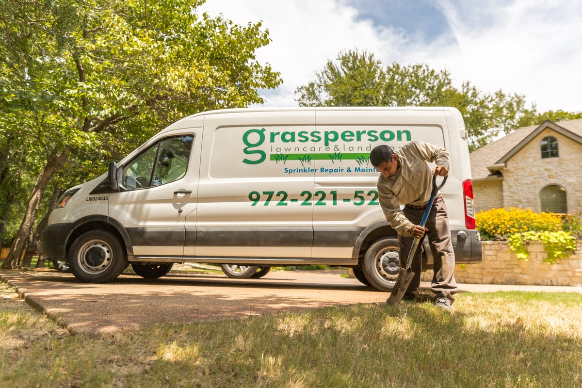 grassperson van with irrigation technician digging to fix irrigation