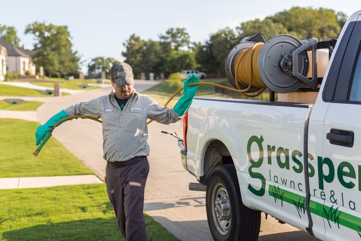 lawn care technician pulls hose off of reel to spray lawn