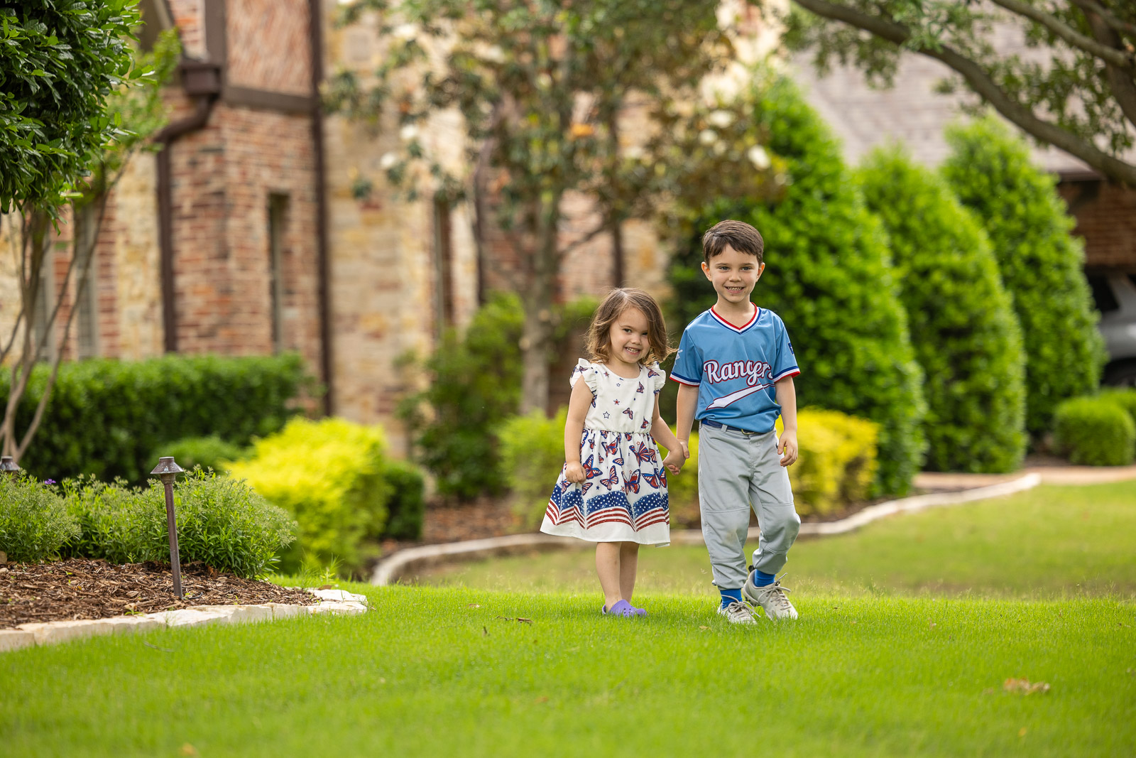 childrensmiling on green lawn landscape beds 