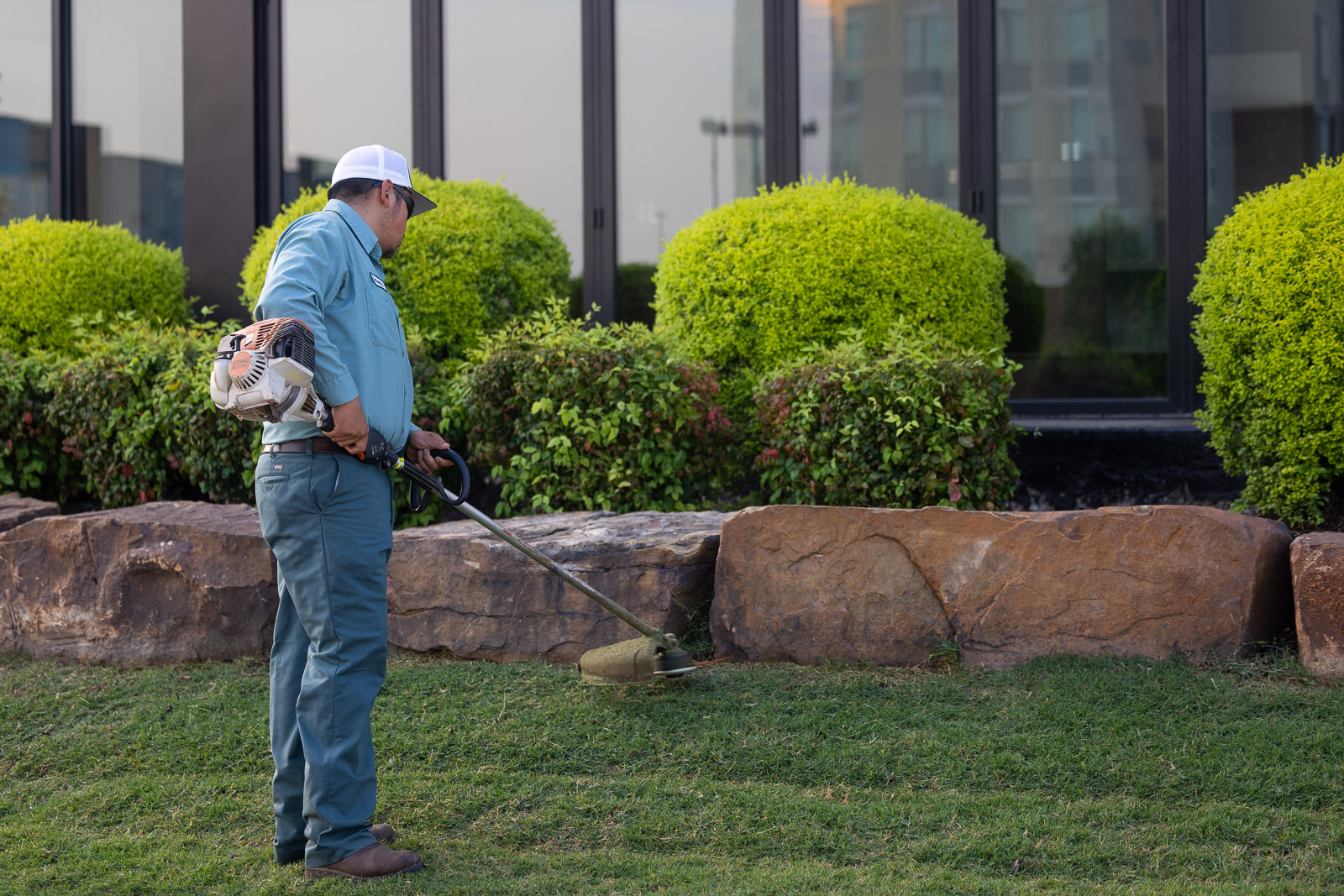 commercial landscape maintenance crew weed wacking landscape beds 2