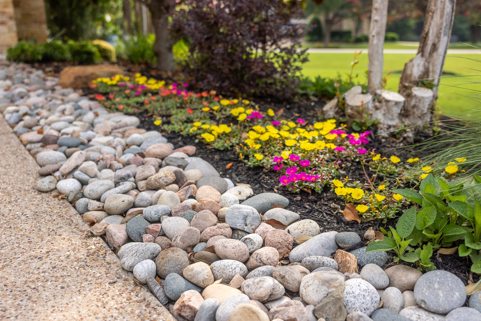 dry river rocks along sidewalk and landscape bed 