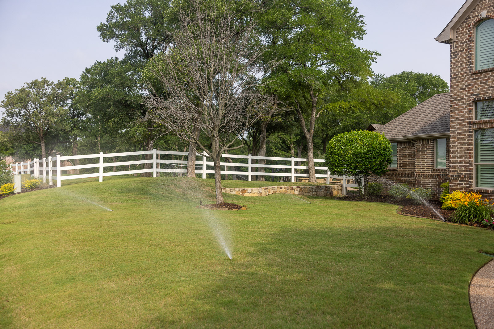 irrigation system watering large green lawn front of house 