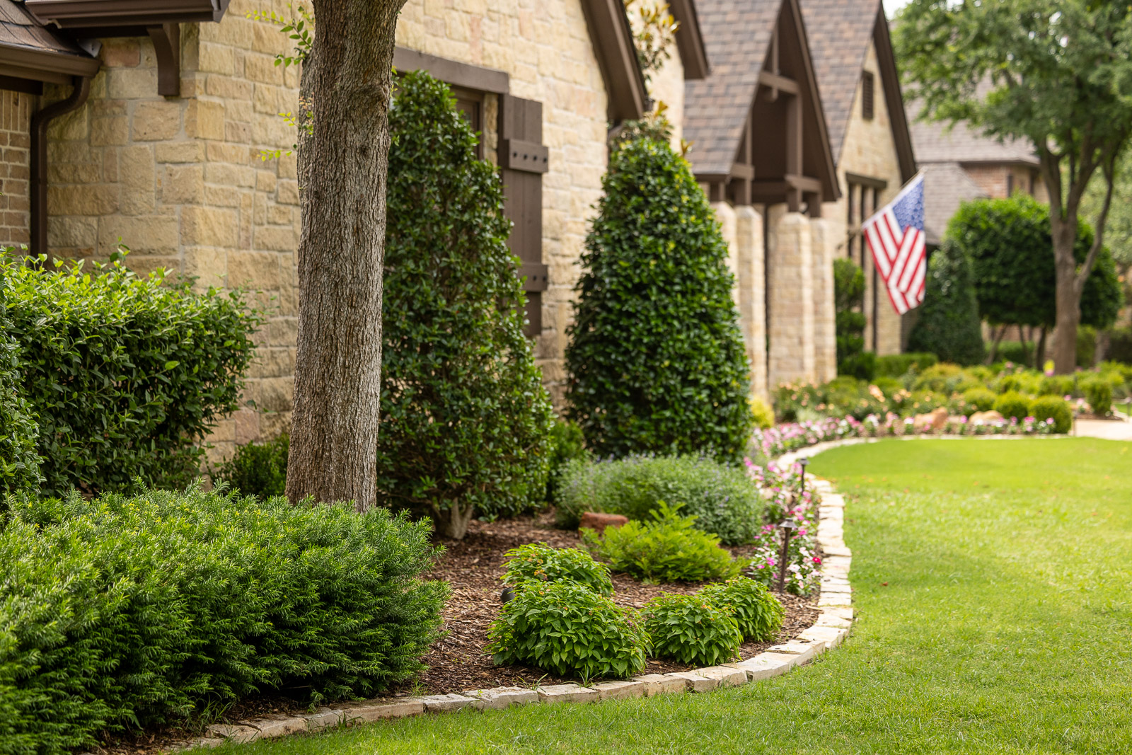 landscape beds front of house flag in background 